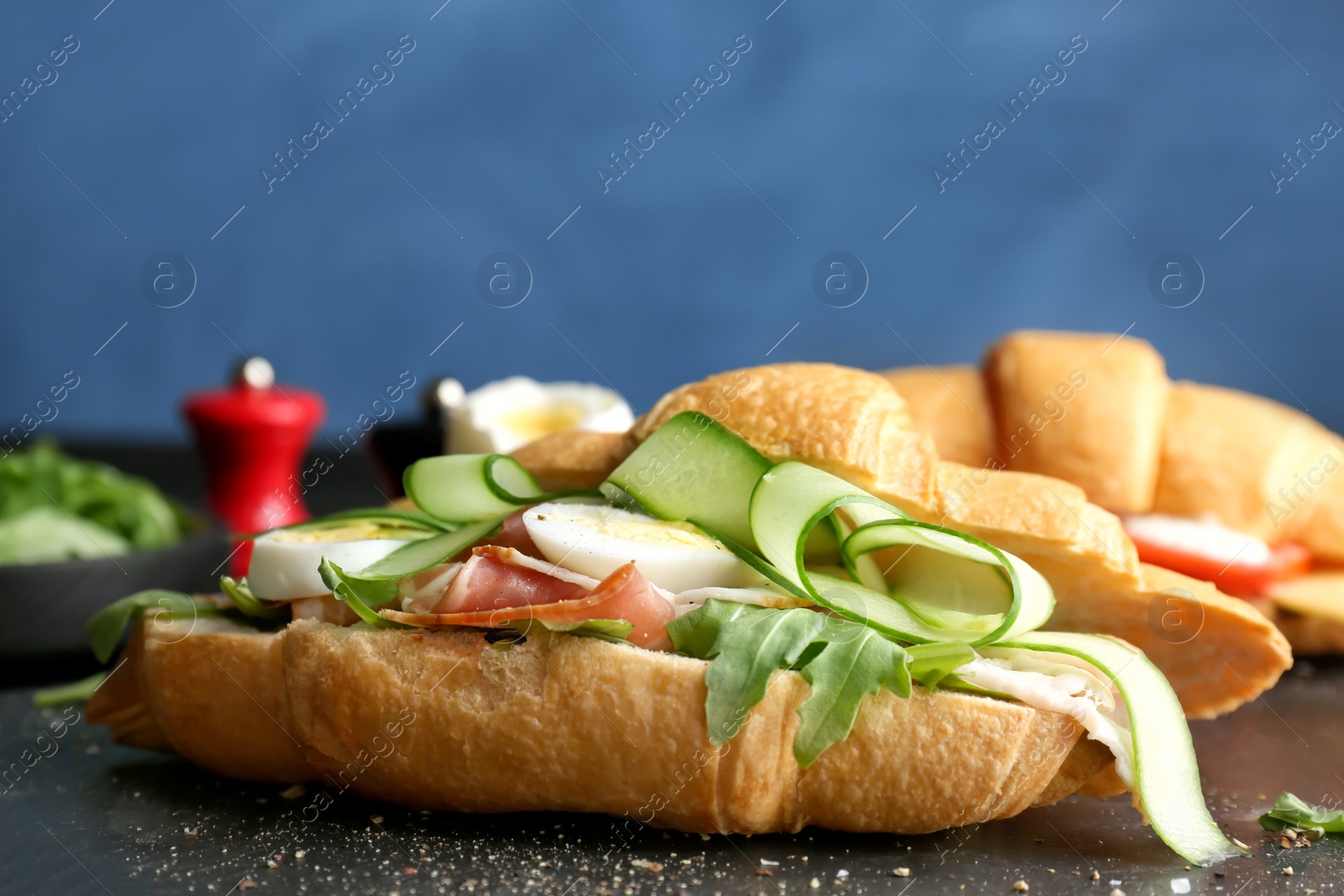 Photo of Tasty croissant sandwich with bacon on table