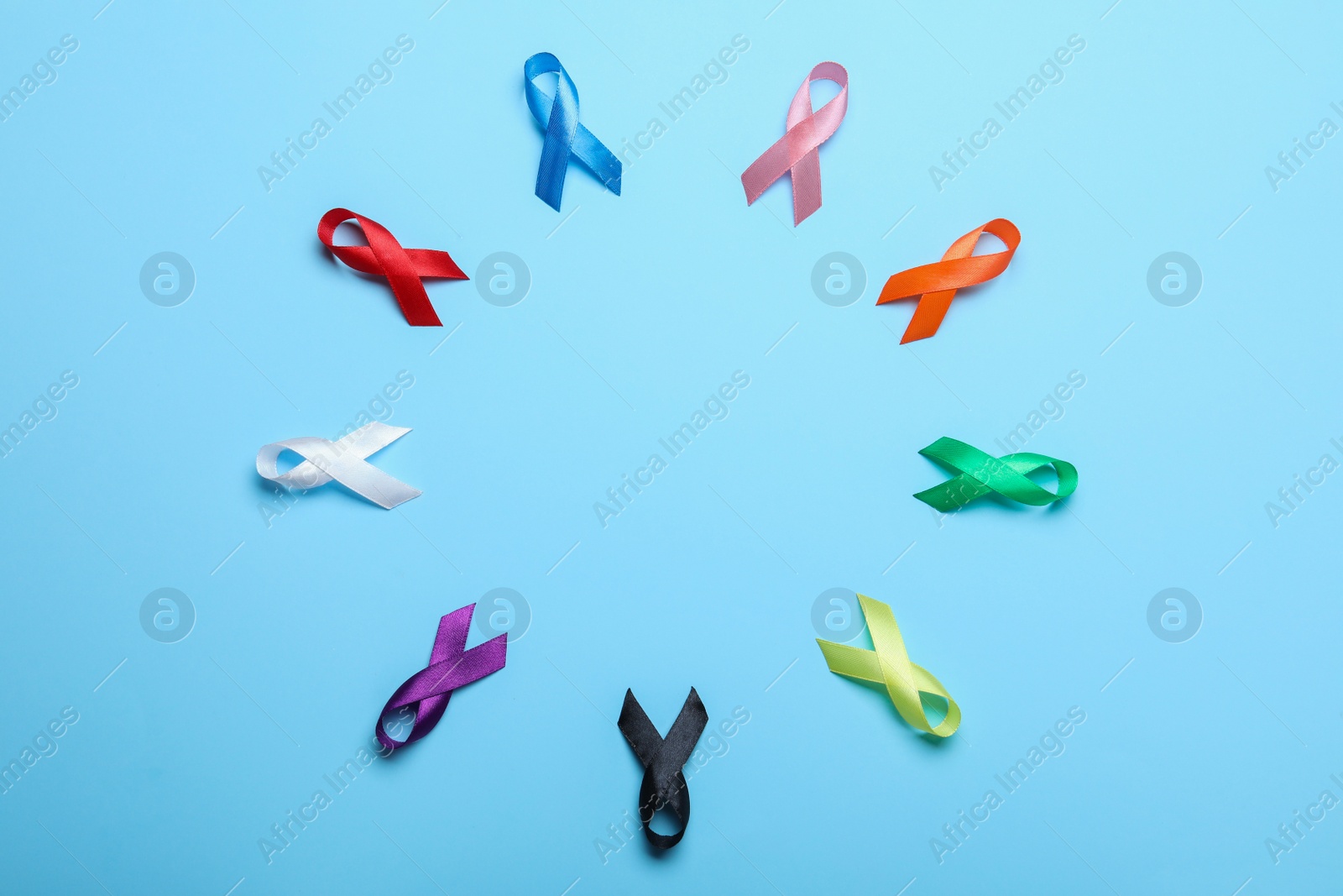 Photo of Frame of colorful ribbons on light blue background, flat lay with space for text. World Cancer Day