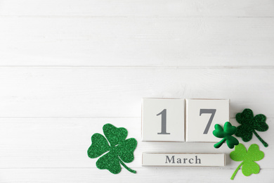 Photo of Flat lay composition with block calendar on white wooden background, space for text. St. Patrick's Day celebration