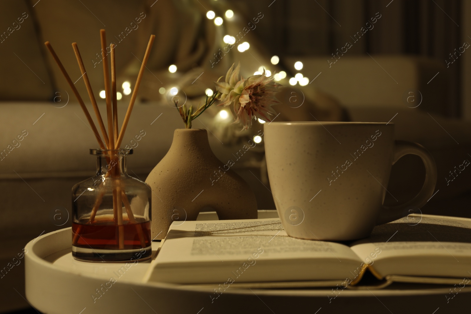 Photo of Cup of drink, air freshener and book on table indoors