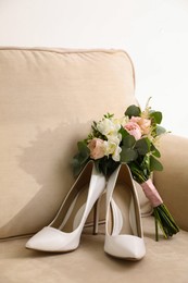 Photo of Pair of white wedding high heel shoes and beautiful bouquet on sofa indoors