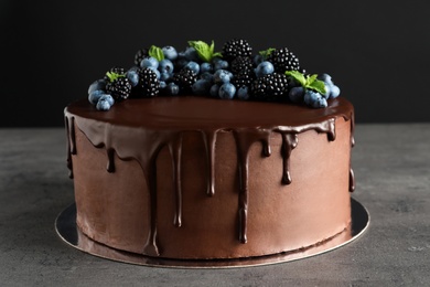 Fresh delicious homemade chocolate cake with berries on table against dark background