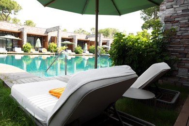 Photo of Sunbeds near outdoor swimming pool at luxury resort