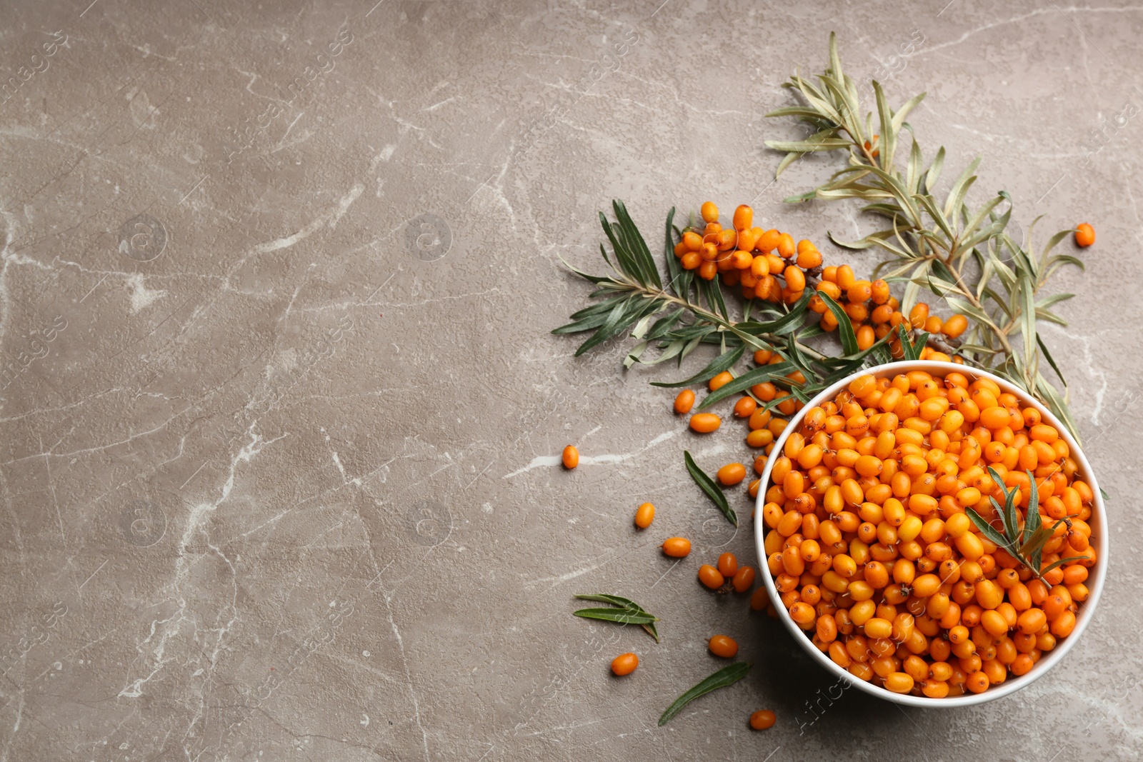 Photo of Ripe sea buckthorn berries on marble table, flat lay. Space for text