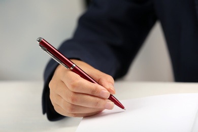 Photo of Writer signing autograph in book at table, closeup