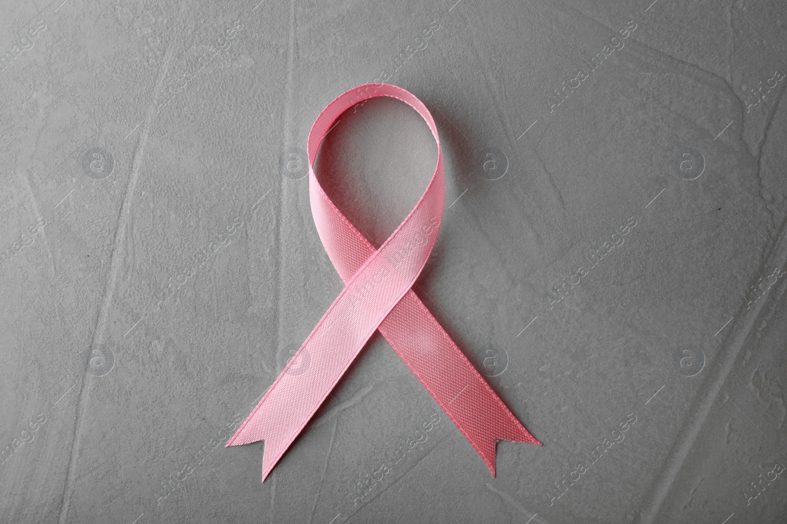 Photo of Pink ribbon on grey background, top view. Breast cancer awareness concept