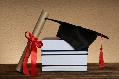 Graduation hat, books and diploma on wooden table