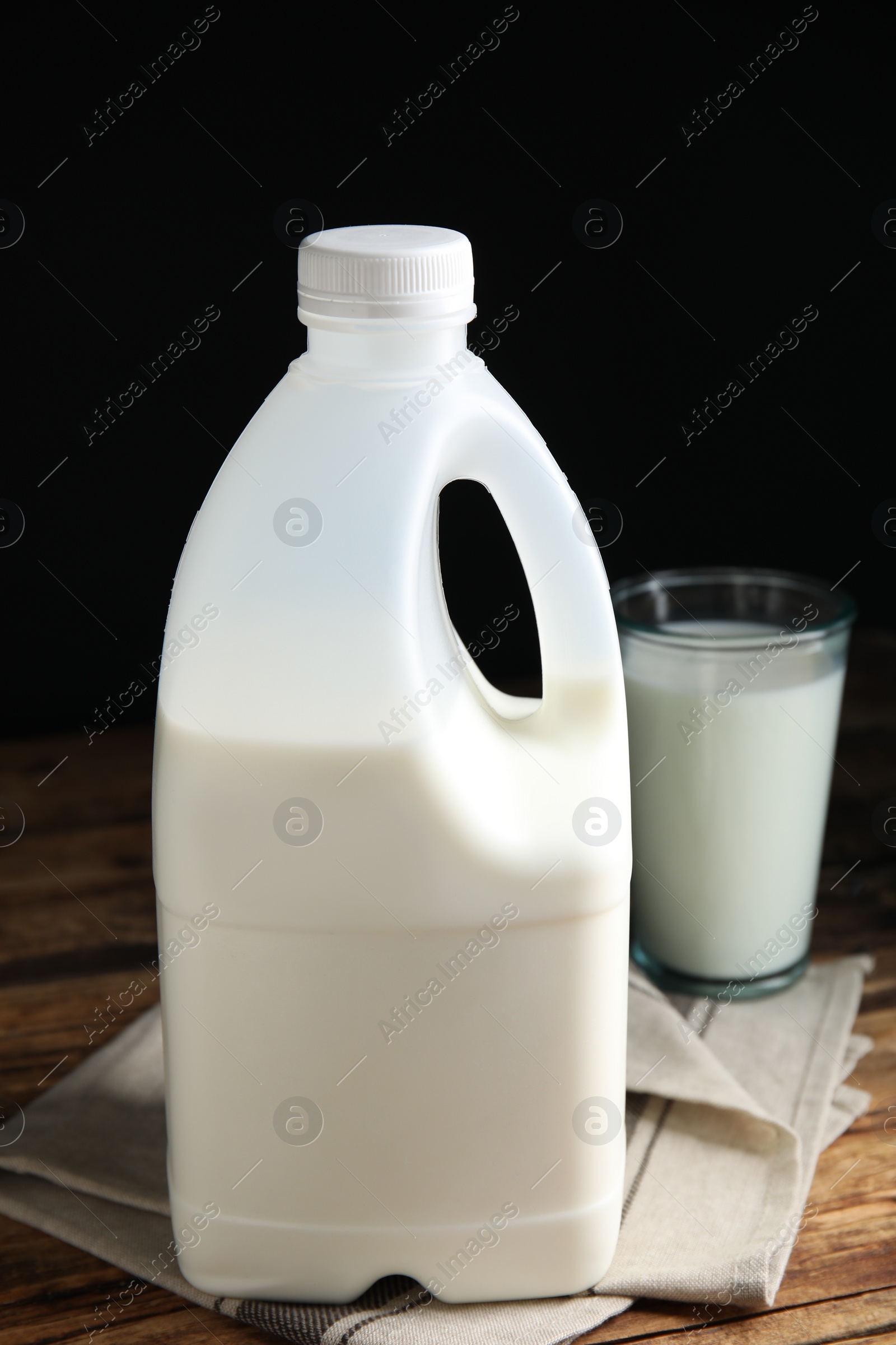 Photo of Gallon bottle and glass of milk on wooden table