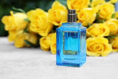 Perfume and beautiful bouquet of yellow roses on light table, selective focus. Space for text