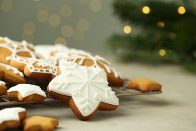 Photo of Tasty Christmas cookies with icing on table against blurred lights, closeup. Space for text