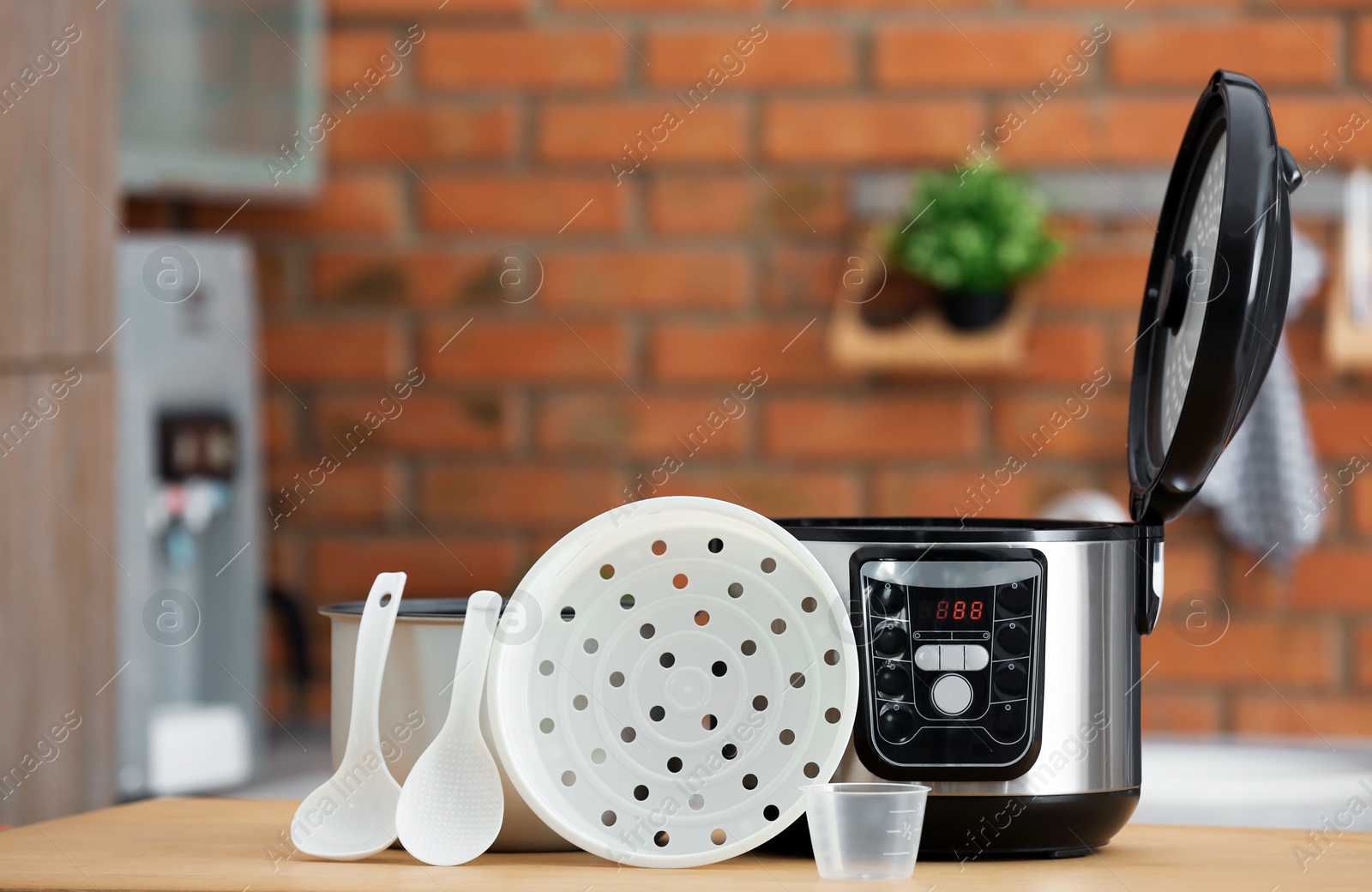 Photo of Modern electric multi cooker, parts and accessories on table in kitchen. Space for text