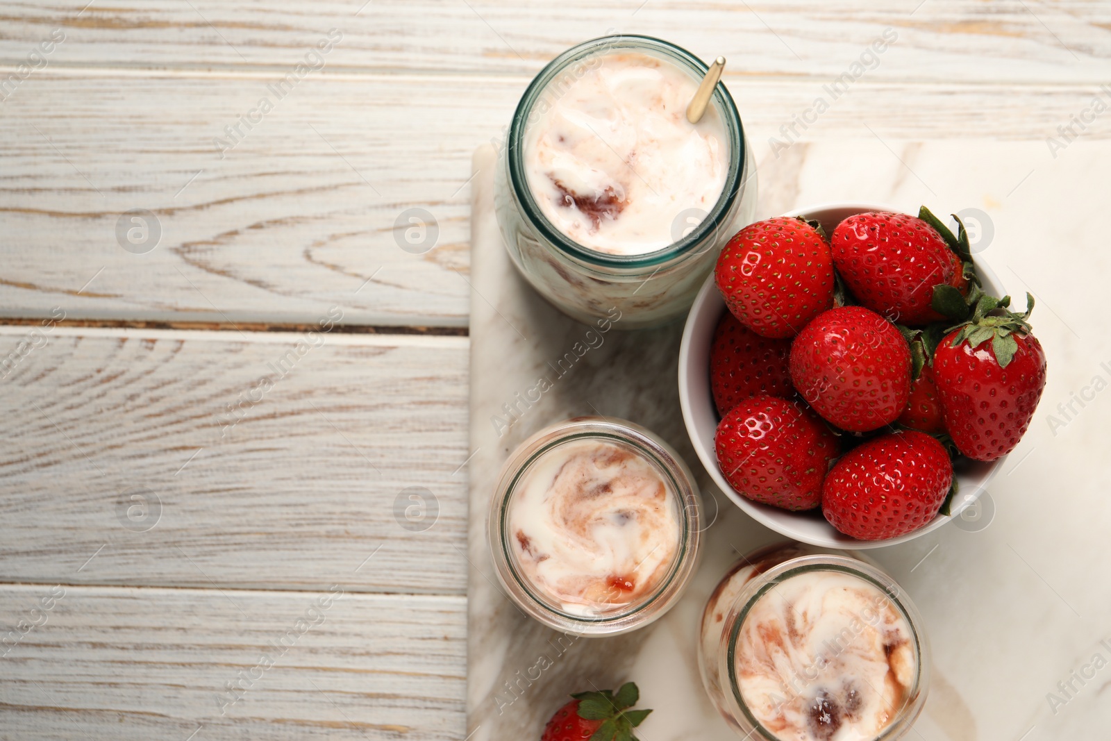 Photo of Tasty yoghurt with jam and strawberries on white wooden table, top view. Space for text