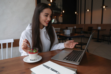 Photo of Young blogger working with laptop in cafe