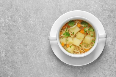 Dish of fresh homemade vegetable soup on light grey background, top view. Space for text