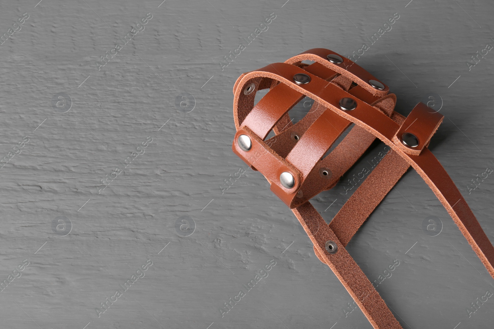 Photo of Brown leather dog muzzle on gray wooden table, top view. Space for text