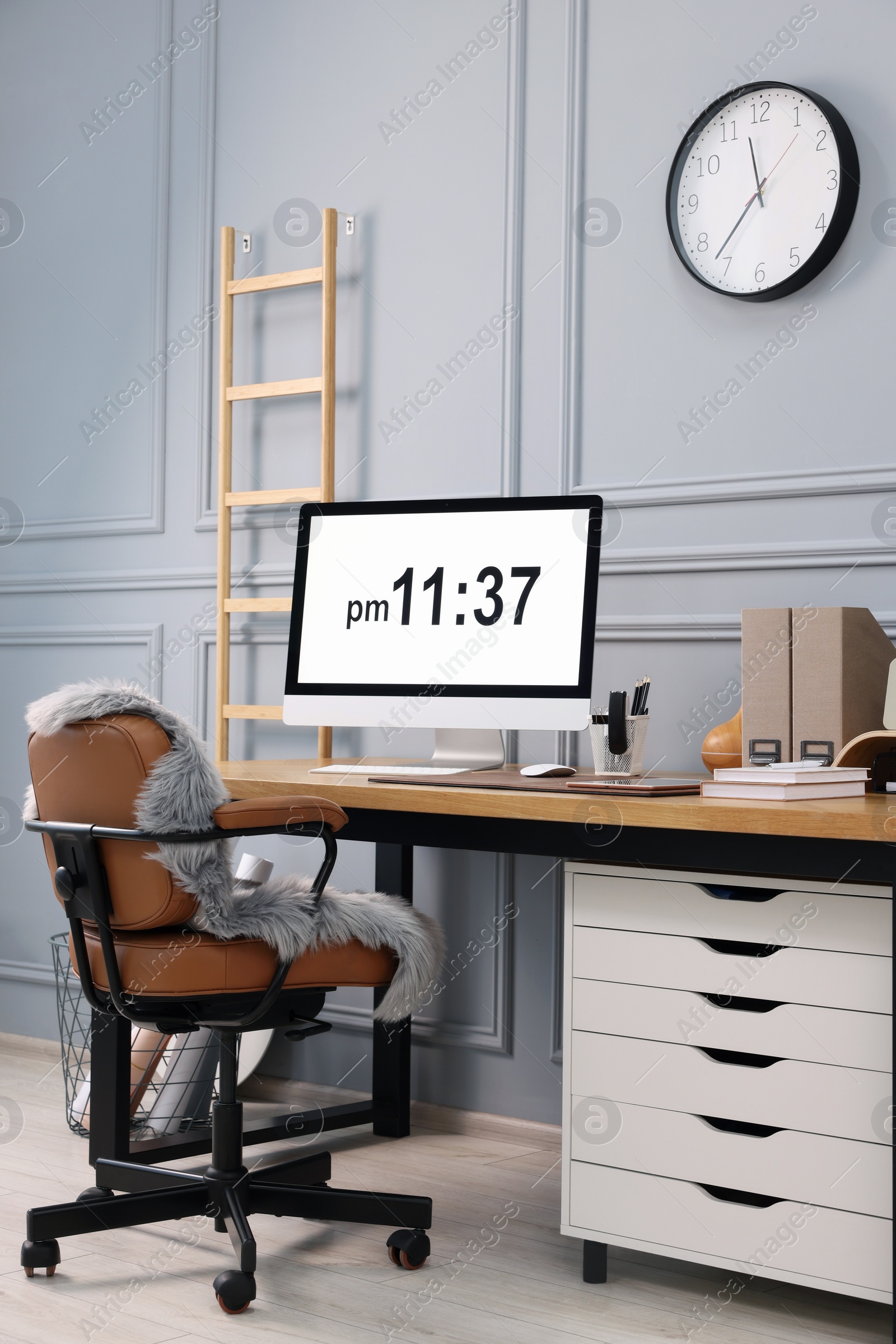 Photo of Stylish workplace with computer and stationery on wooden desk near grey wall at home