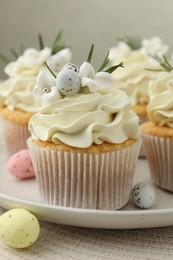 Tasty Easter cupcakes with vanilla cream and candies on table, closeup