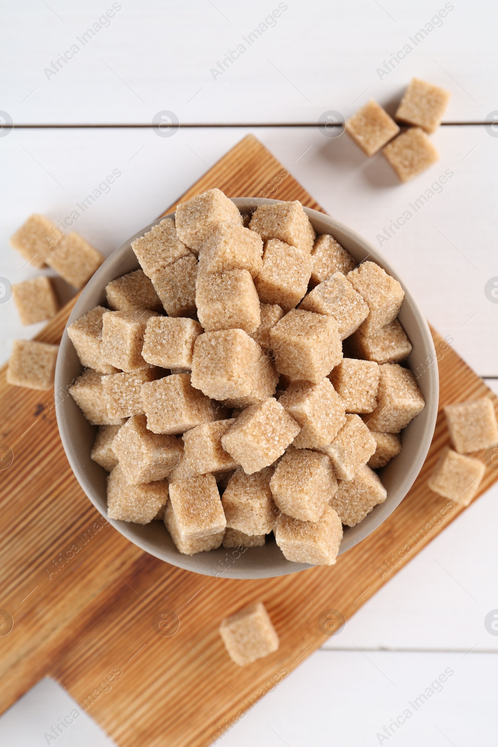 Photo of Brown sugar cubes on white wooden table, flat lay