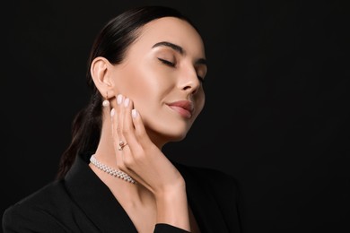 Photo of Young woman with elegant pearl jewelry on black background, space for text