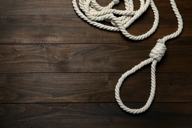 Photo of Rope noose on wooden table, top view. Space for text