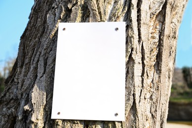 Photo of Empty signboard on tree trunk outdoors. Space for design