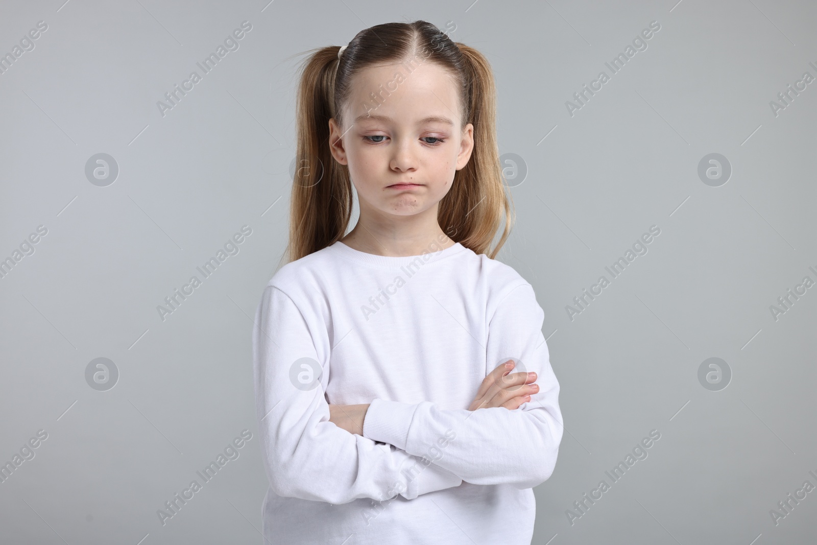 Photo of Portrait of sad girl with crossed arms on light grey background