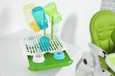 Dryer with baby bottles and nipples after sterilization on white table indoors