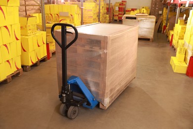 Manual forklift with wrapped pallets in warehouse. Logistics concept