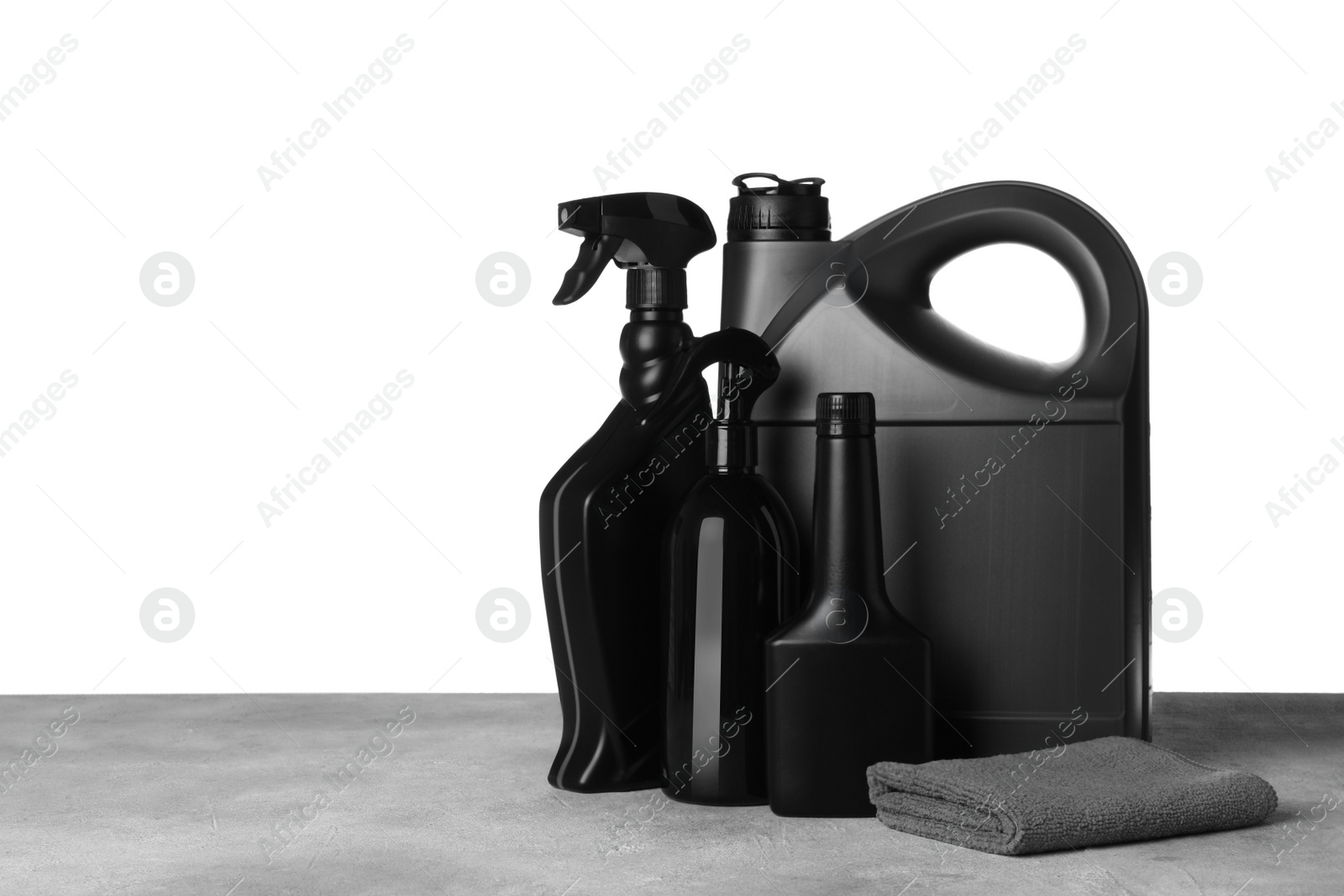 Photo of Bottles, canister and car wash cloth on grey table against white background