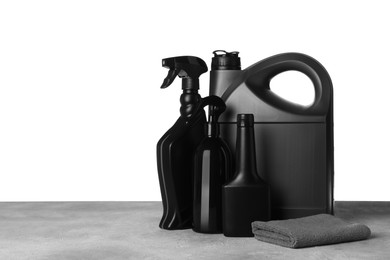 Photo of Bottles, canister and car wash cloth on grey table against white background