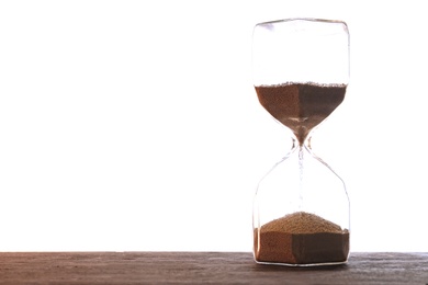 Hourglass with flowing sand on table against light background. Time management