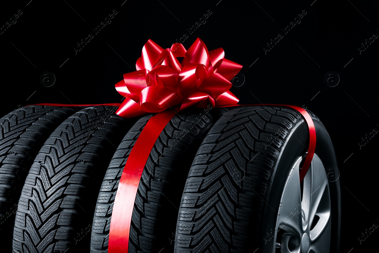 Photo of Gift set of wheels with winter tires on black background, closeup