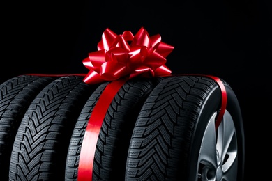 Photo of Gift set of wheels with winter tires on black background, closeup