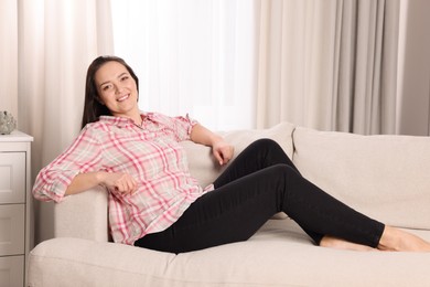 Photo of Beautiful overweight woman sitting on sofa at home