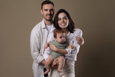 Photo of Happy family. Couple with their cute baby on beige background