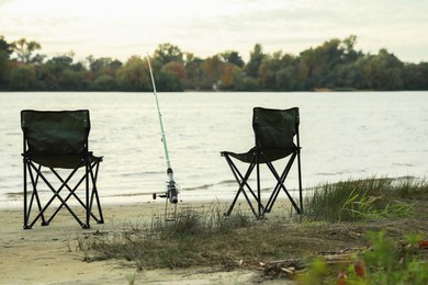 Photo of Folding chairs and fishing rod at riverside