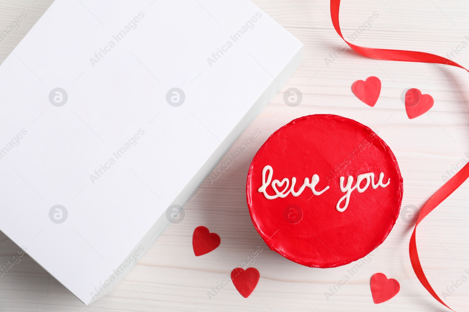 Photo of Bento cake with text Love You and takeaway packaging on white wooden table, flat lay