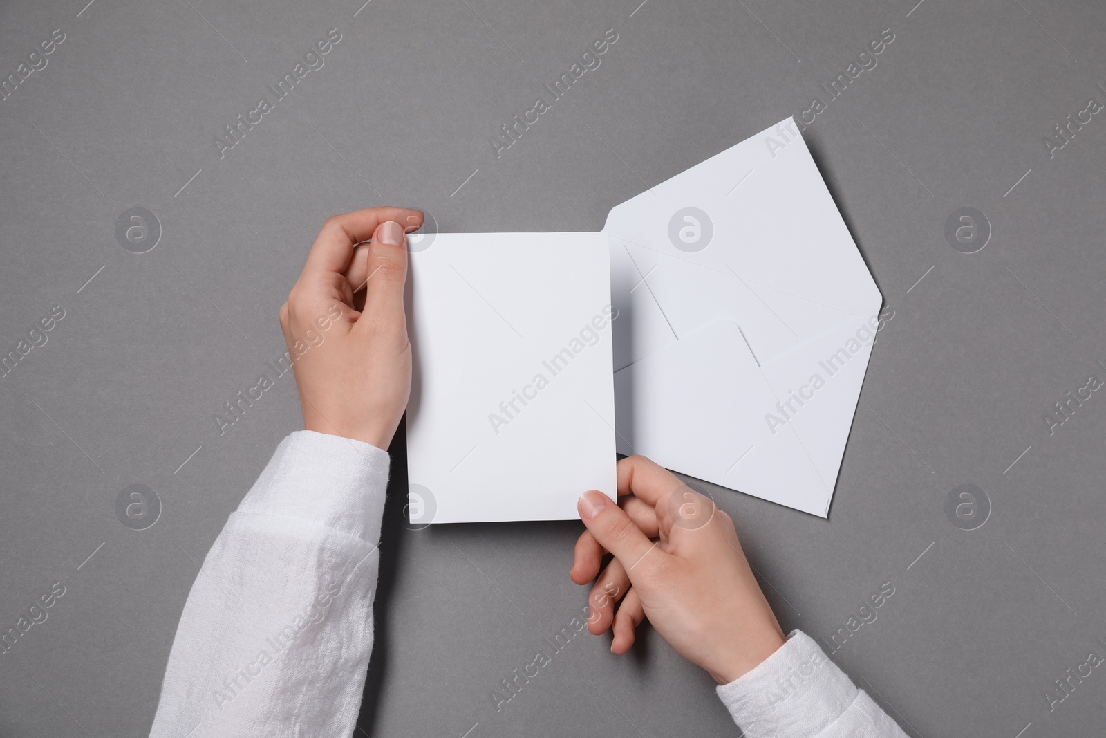 Photo of Woman with blank card at grey table, top view. Space for text