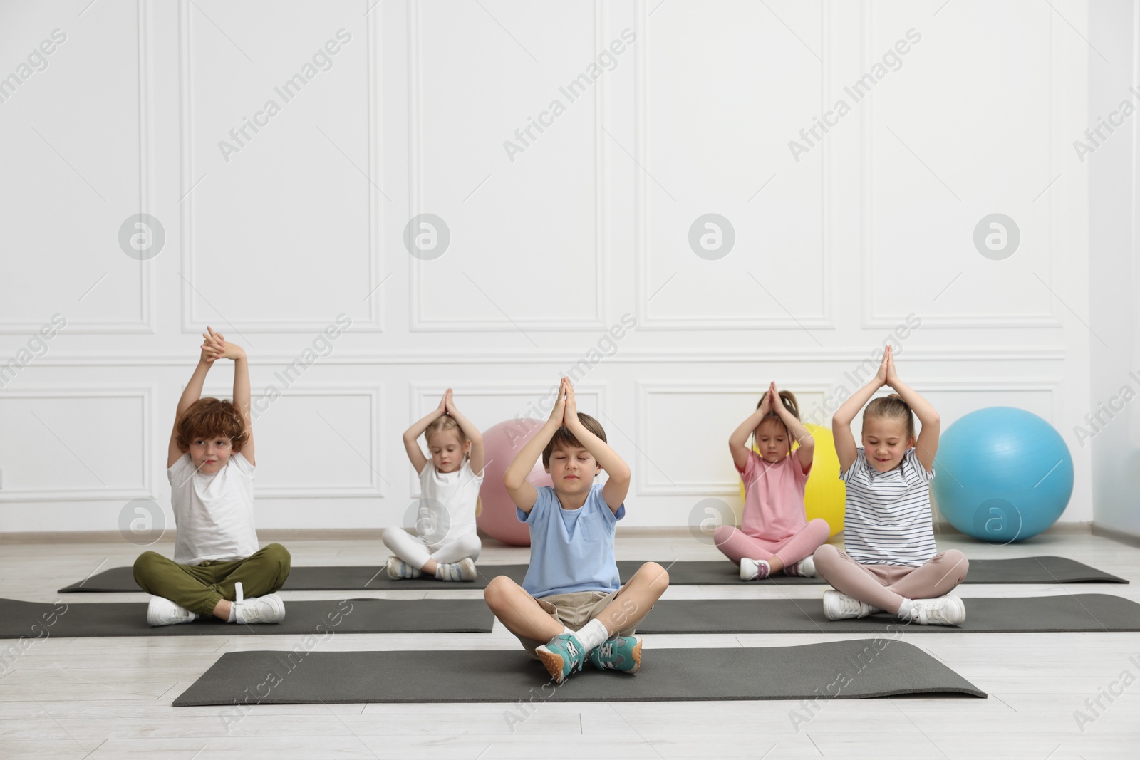 Photo of Group of children doing gymnastic exercises on mats indoors