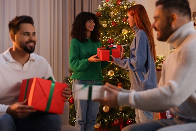 Photo of Christmas celebration. Happy friends exchanging gifts at home, selective focus