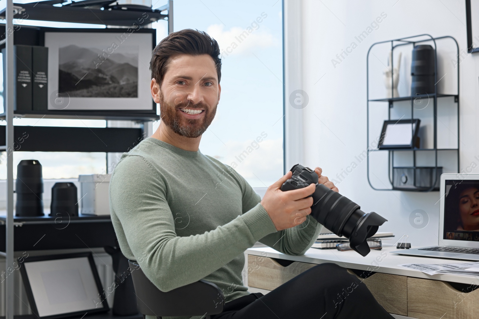 Photo of Professional photographer with digital camera at table in office