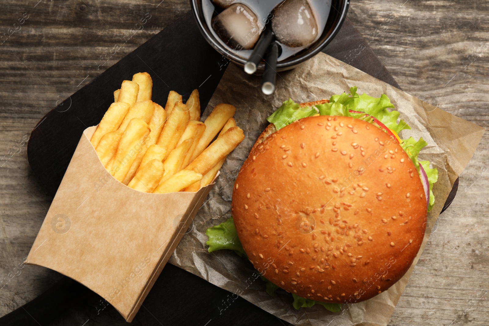 Photo of French fries, tasty burger and drink on wooden table, top view