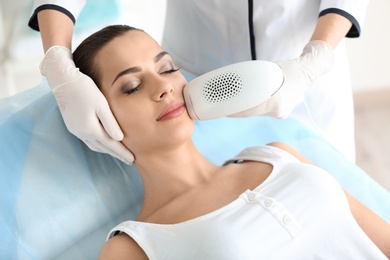 Photo of Woman undergoing hair removal procedure with photo epilator in salon