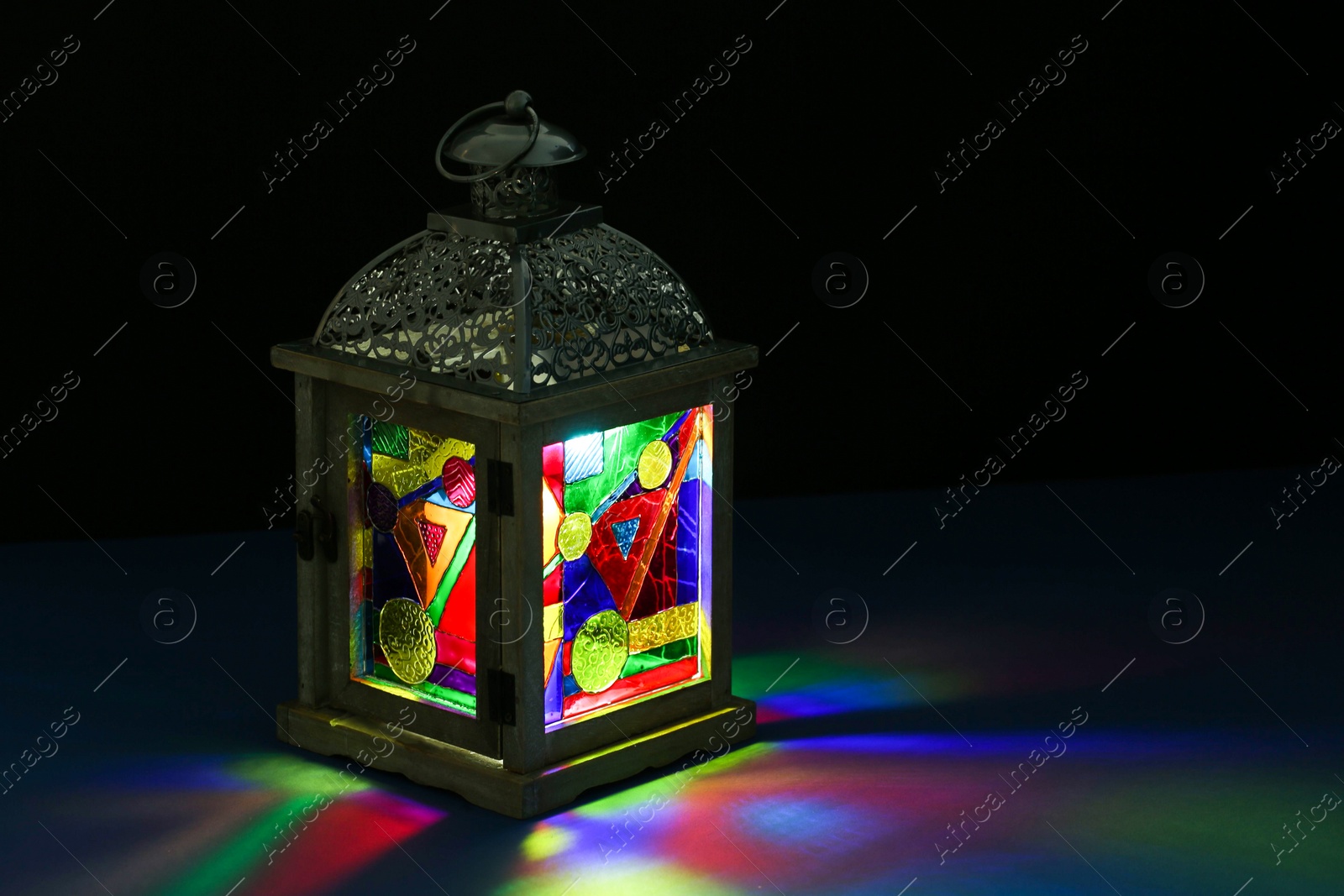 Photo of Decorative Arabic lantern on table against dark background. Space for text