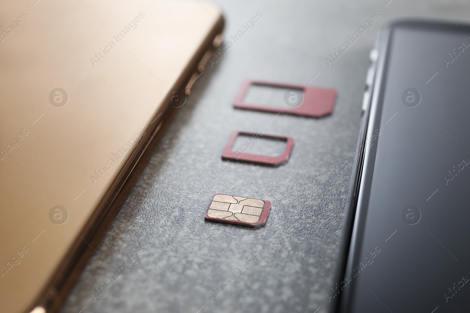Photo of SIM card and mobile phones on grey table, closeup