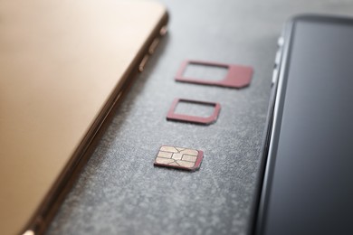 Photo of SIM card and mobile phones on grey table, closeup