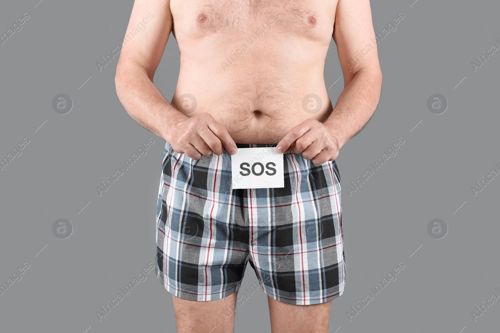 Photo of Mature man with urological problems holding SOS sign on grey background