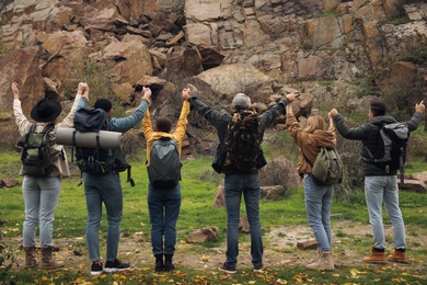 Photo of Group of hikers with backpacks in mountains, back view