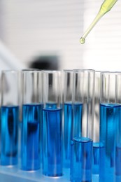 Laboratory analysis. Dripping liquid into test tubes indoors, closeup