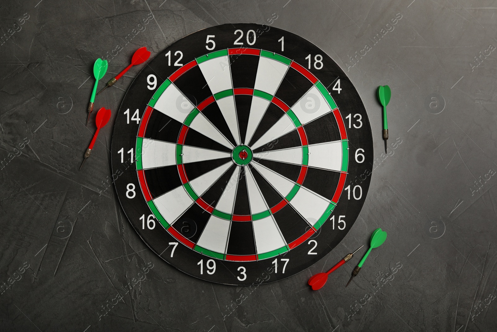 Photo of Dart board with color arrows on grey stone background, top view